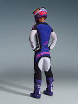 Pilota di motocross visto di spalle con equipaggiamento completo da gara, maglia Techstar Knif 2026 con parte posteriore blu e maniche traforate bianche, pantaloni neri coordinati con logo Alpinestars rosa, casco multicolore e stivali viola, outfit coordinato per competizioni off-road.