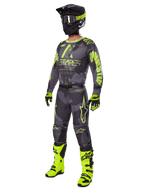 Pilota di motocross con completo Alpinestars 2025 Racer Hollow, maglia e pantaloni Dark Camo e Giallo Fluo, casco nero e giallo fluo, guanti abbinati e stivali giallo fluo brillante, outfit coordinato per gare fuoristrada