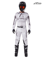 Alpinestars Completo Racer Hollow 2025, maglia e pantaloni da motocross da uomo in marrone chiaro mimetico e bianco, vista frontale in studio su un modello che indossa casco, guanti e stivali abbinati, abbigliamento da fuoristrada leggero e ad alte prestazioni