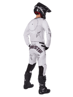 Alpinestars 2025 Racer Hollow Gear Set, bianco, vista posteriore di un pilota di motocross che indossa maglia e pantaloni bianchi con branding nero, casco nero e stivali neri, abbigliamento professionale coordinato per gare fuoristrada
