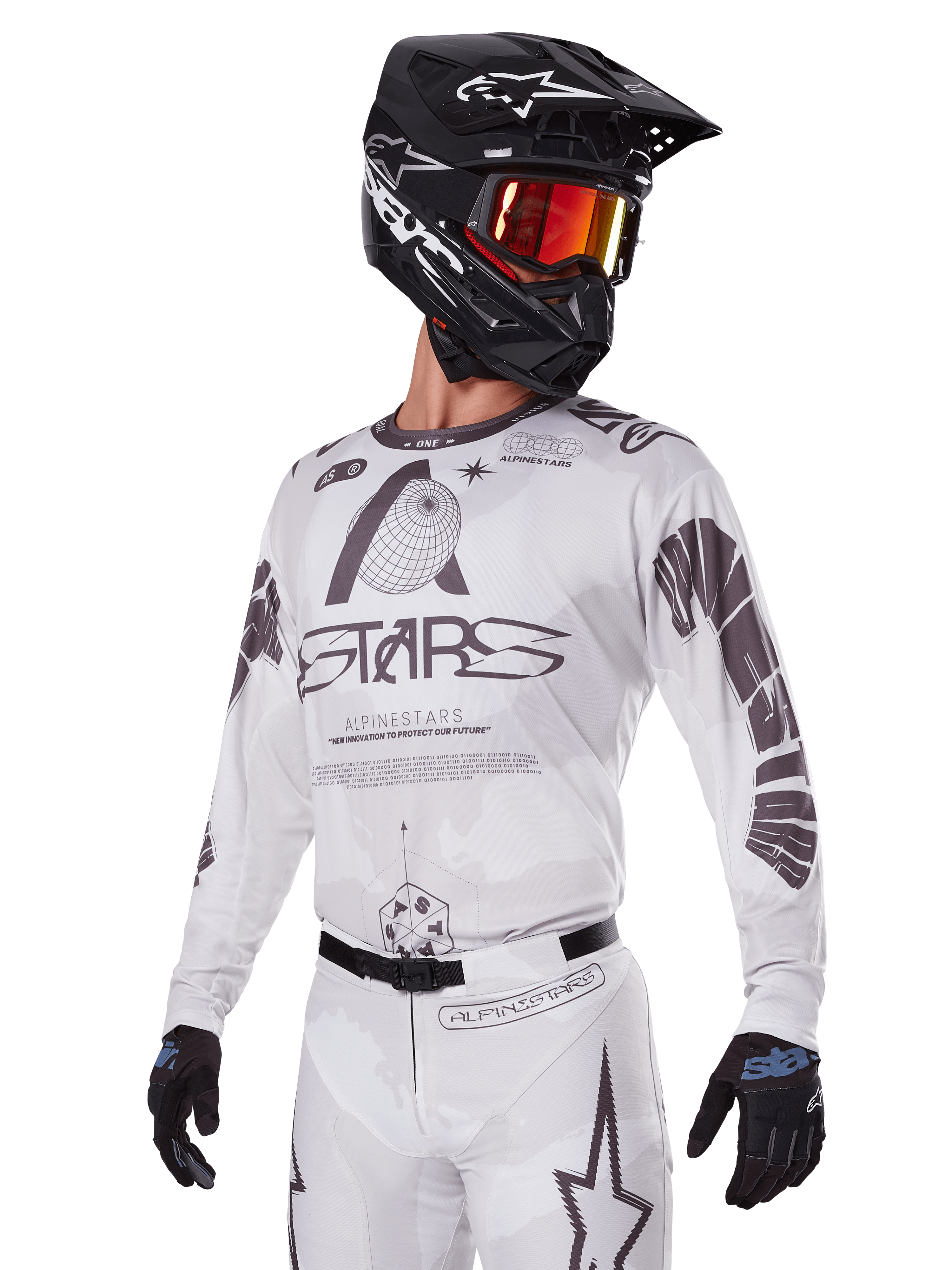 Alpinestars 2025 Racer Hollow Gear Set, maglia e pantaloni da motocross, bianco con grafiche nere e grigie, con marchio 'ASTARS' e motivi a globo, indossato con casco nero, occhiali a specchio rossi e guanti neri, progettato per prestazioni fuoristrada