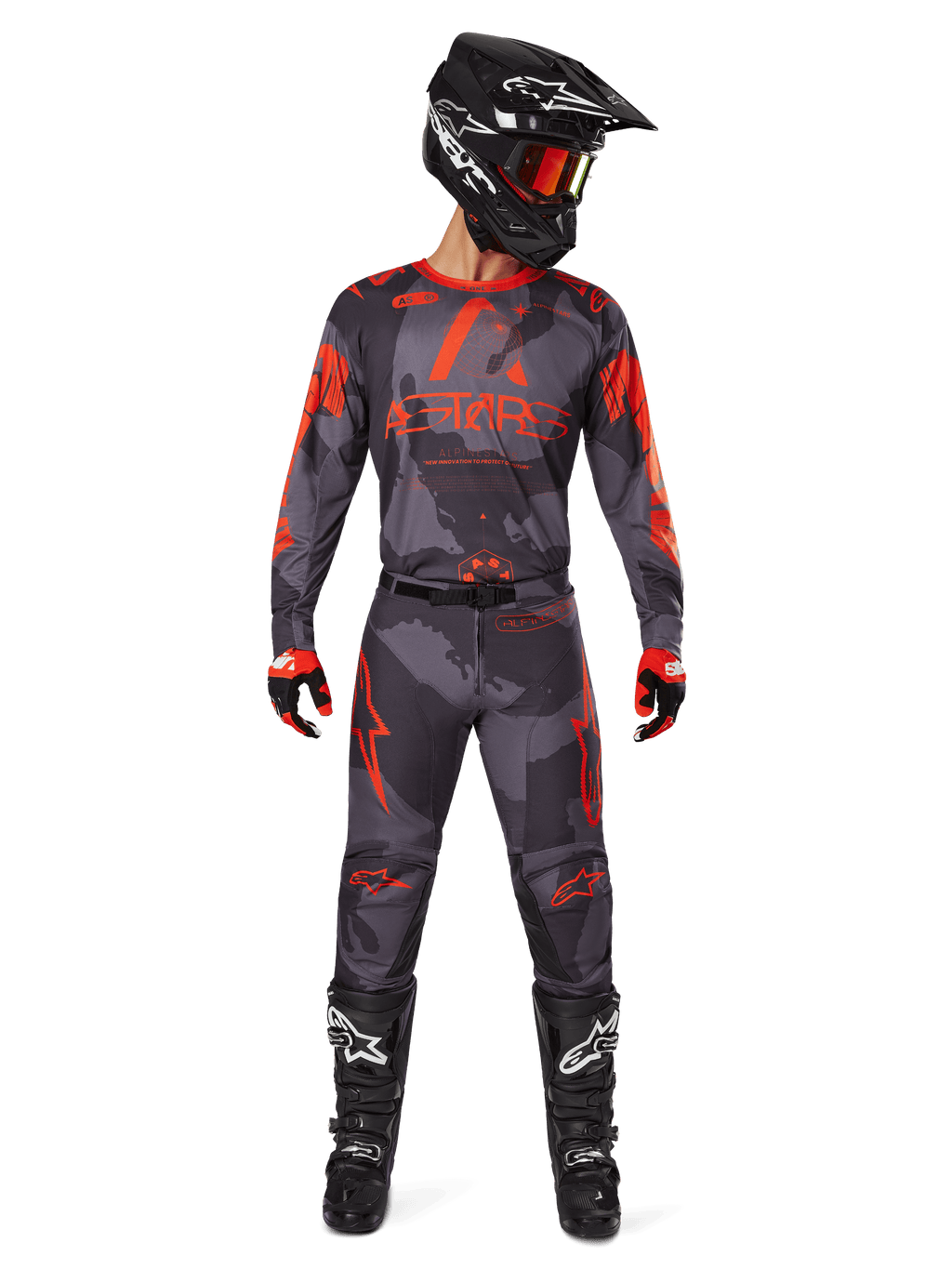 Pilota di motocross con maglia Alpinestars Racer Hollow 2025 e pantaloni abbinati in Grigio Camo Arancione Fluo, set completo con casco nero, occhiali, guanti e stivali, loghi arancioni e grafica mimetica