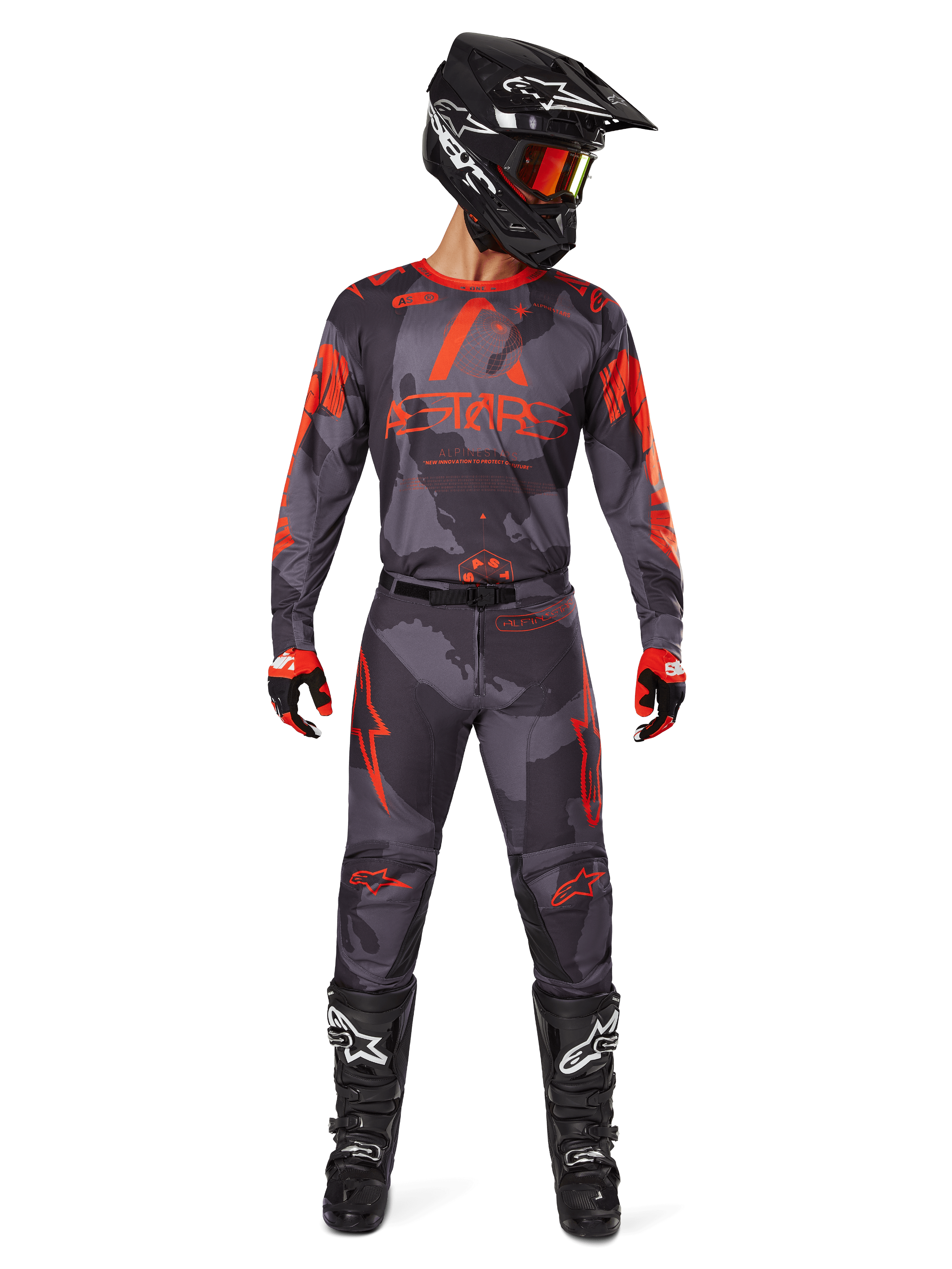 Pilota di motocross con maglia Alpinestars Racer Hollow 2025 e pantaloni abbinati in Grigio Camo Arancione Fluo, set completo con casco nero, occhiali, guanti e stivali, loghi arancioni e grafica mimetica