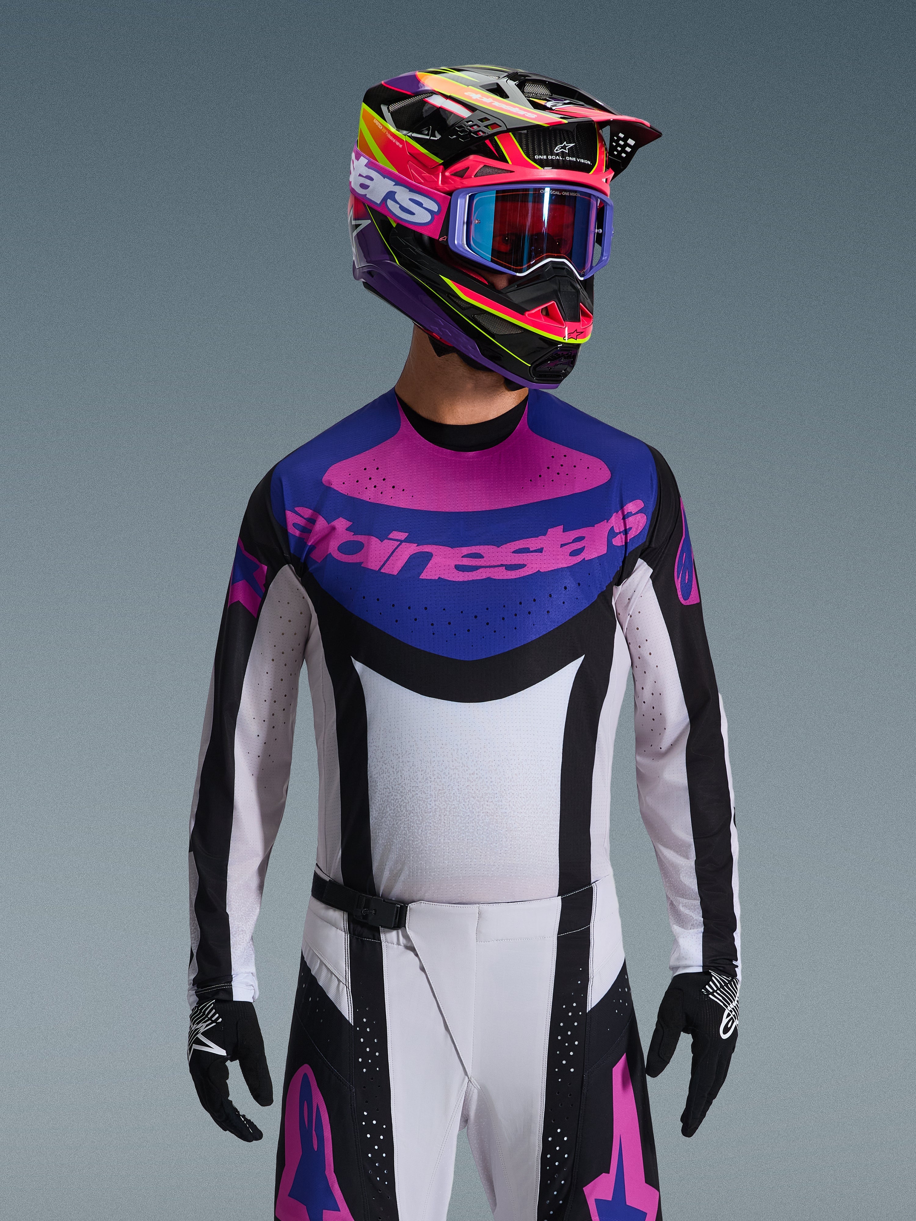 Alpinestars Techstar Knif Jersey 2026, maglia da motocross, nero, grigio chiaro e viola, logo Alpinestars rosa sul petto, indossata con casco colorato e pantaloni da motocross coordinati, vestibilità atletica da gara con perforazioni tagliate al laser per la ventilazione