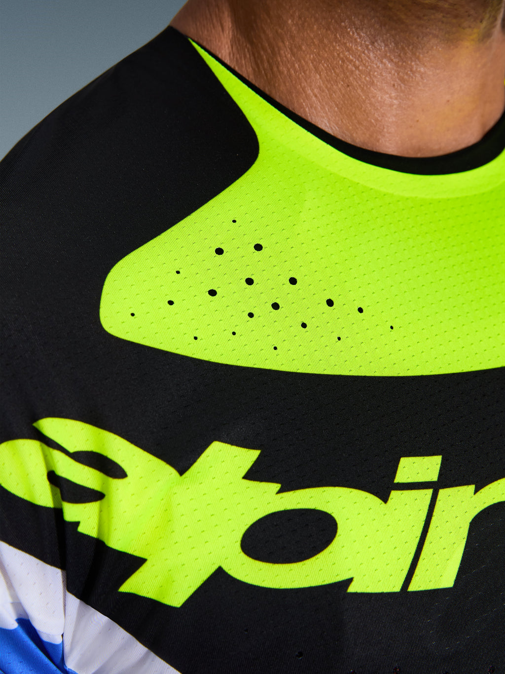 Primo piano della maglia Alpinestars Techstar Knif 2026, nero e giallo fluo, che mette in risalto le perforazioni tagliate al laser per la ventilazione, il colletto incollato senza cuciture e il tessuto tecnico traspirante con logo giallo.