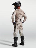 Alpinestars Maglia Racer Lone, maglia da motocross da uomo, mimetico desert e nero, vista posteriore con casco e stivali.