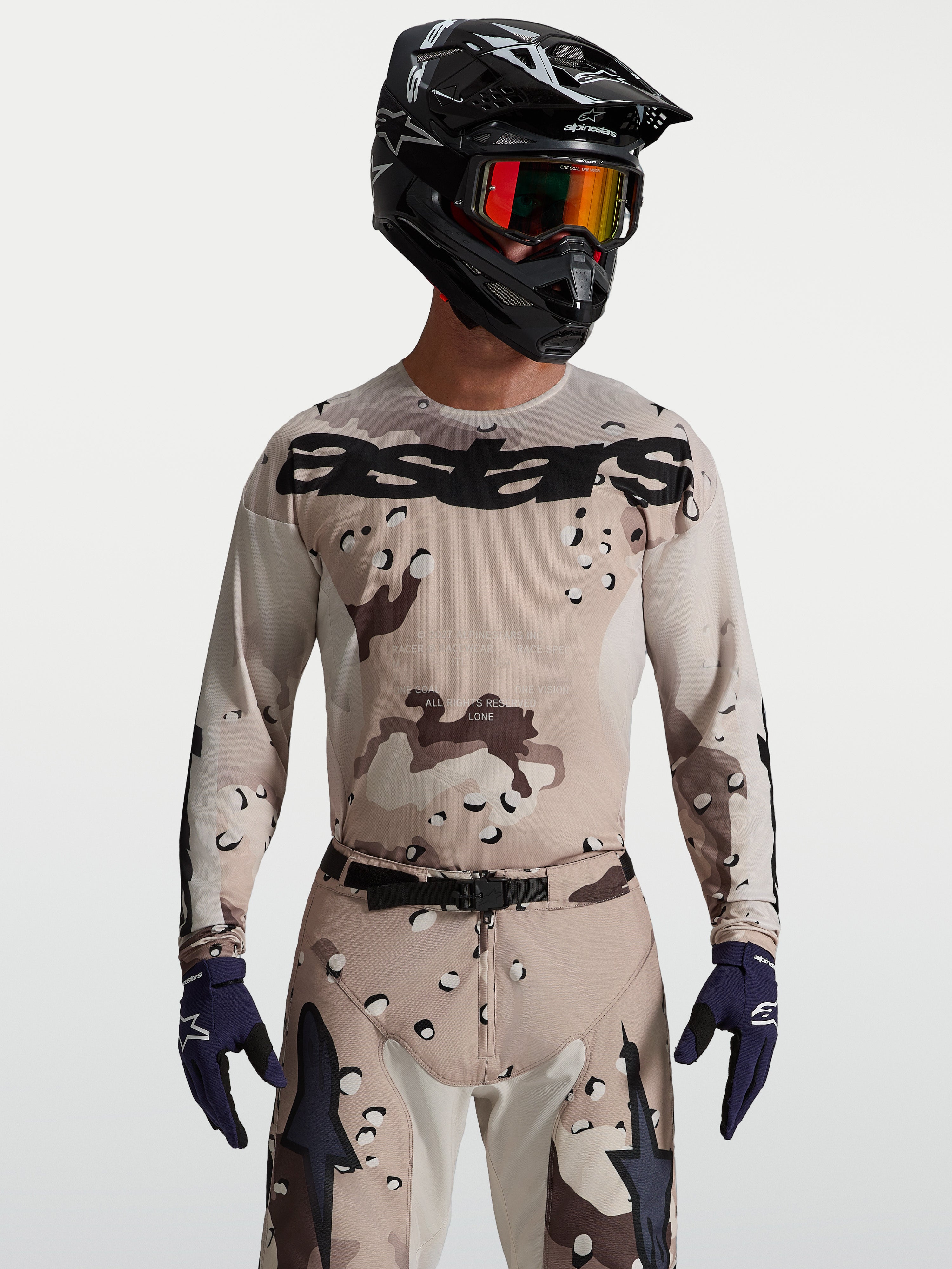 Alpinestars Maglia Racer Lone, maglia da motocross da uomo, camouflage deserto e nero, indossata con casco e maschera.