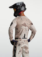 Alpinestars Maglia Racer Lone, maglia da motocross da uomo, sabbia e nero con motivo desert camo, vista posteriore su modello con casco, tessuto tecnico traspirante per sessioni off-road e enduro