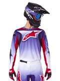 Alpinestars 2025 Fluid Wurx Jersey, maglia da motocross, sfumatura da viola a bianco, logo a stella rosso e accenti rossi, vestibilità atletica, indossata con pantaloni coordinati, casco nero e guanti rossi