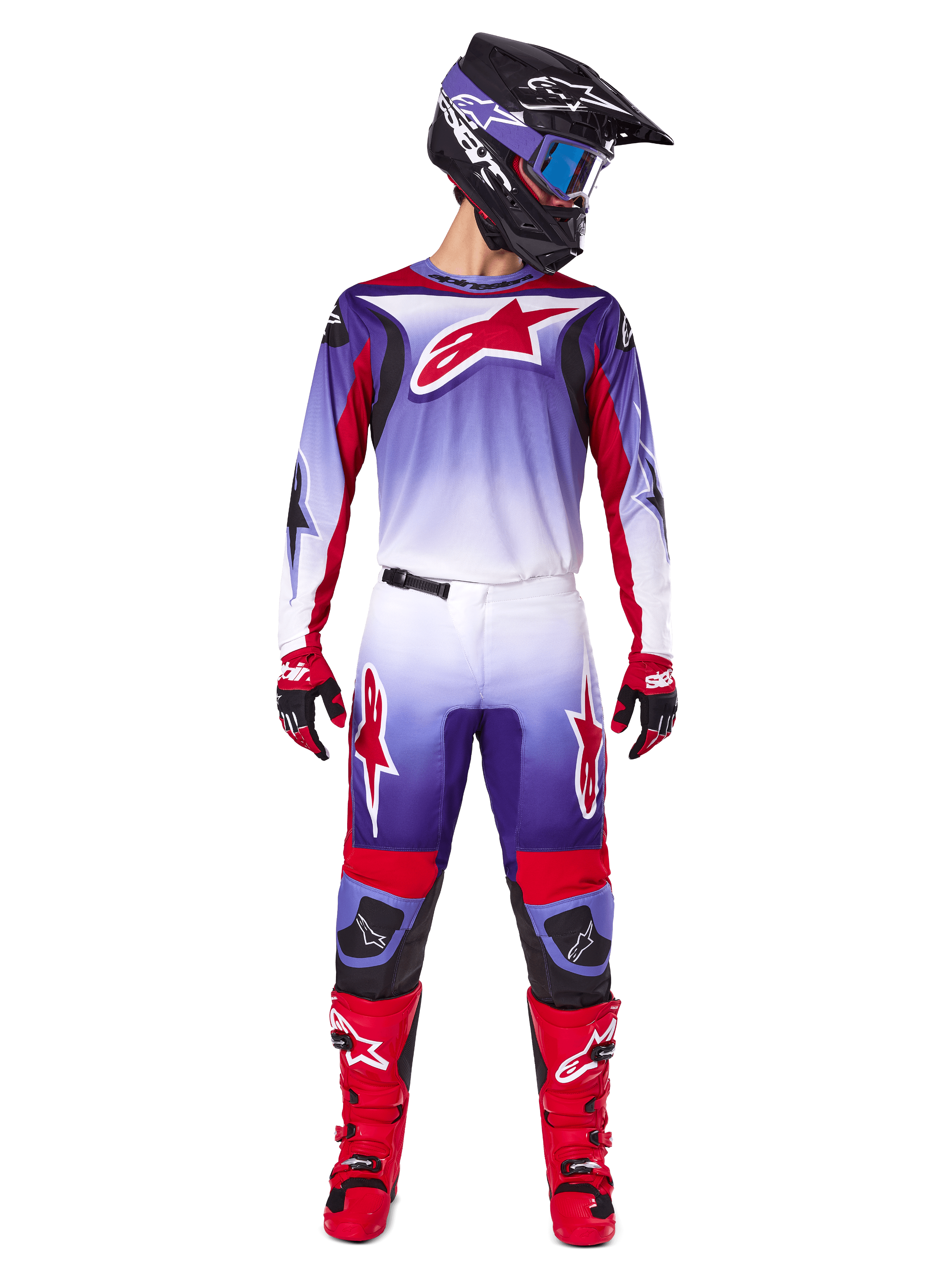 Pilota di motocross con abbigliamento completo Alpinestars, maglia Fluid Wurx 2025 in Purple Bright Red con dettagli bianchi e grande logo a stella rosso, pantaloni coordinati, stivali rossi e casco nero con occhiali, outfit coordinato per gare fuoristrada