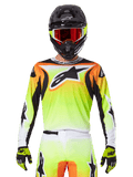 Alpinestars 2025 Fluid Wurx Jersey, maglia da motocross, giallo neon, arancione e bianco, indossata con pantaloni coordinati e casco nero con occhiali rossi, completo da motocross su pilota