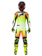 Pilota di motocross con abbigliamento da gara completo, Alpinestars 2025 Fluid Wurx Gear Set, giallo e nero con accenti arancioni e bianchi, maglia con grande logo frontale, pantaloni coordinati, casco nero con occhiali a lenti rosse, stivali giallo neon, outfit coordinato per corse fuoristrada
