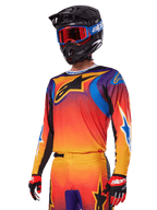Alpinestars 2025 Fluid Wurx Gear Set, completo da motocross, sfumatura arancione, viola e blu, con un grande logo A-stars nero, indossato con casco nero e occhiali blu, outfit coordinato per gare off-road professionali