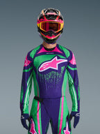 Alpinestars 2026 Techstar Nomur Gear Set, pilota di motocross con maglia da gara verde vivace e viola con accenti rosa, completo coordinato con casco e maschera multicolore, abbigliamento da moto fuoristrada ad alte prestazioni