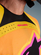 Alpinestars 2026 Techstar Nomur Jersey, maglia da motocross, arancione giallo rosa, dettaglio ravvicinato del petto e del colletto, con ventilazione tagliata al laser, marchio rosa e tessuto mesh traspirante