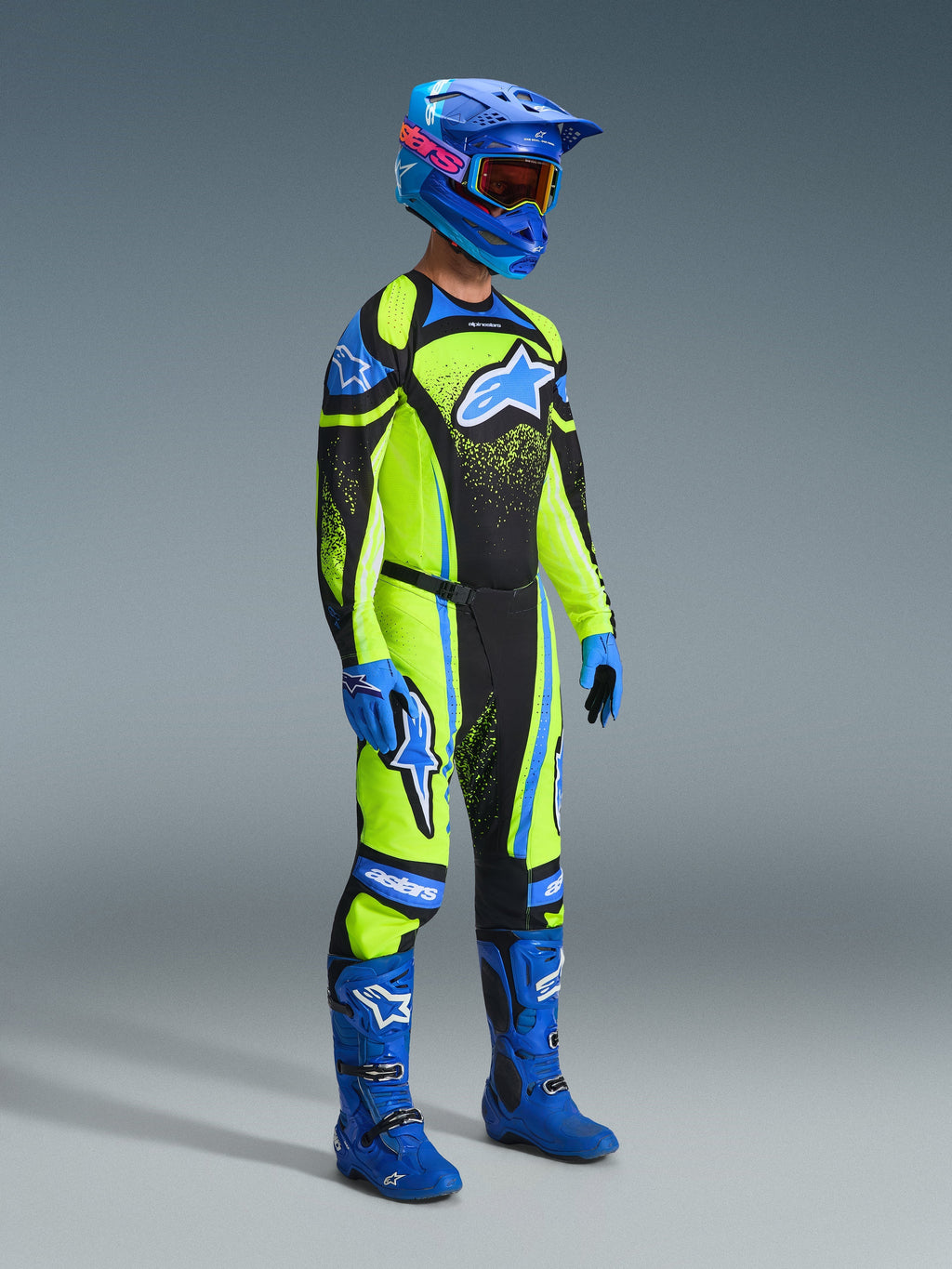Pilota di motocross con abbigliamento completo da gara, maglia Techstar Nomur 2026 in Dark Navy e Yellow Fluo, pantaloni coordinati, casco blu con occhiali, stivali e guanti blu, completo coordinato per gare off-road