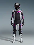 Pilota di motocross con equipaggiamento completo da gara, maglia Alpinestars 2026 Fluid Grid e pantaloni coordinati in nero e grigio chiaro con vivaci accenti viola, casco nero con occhiali viola, stivali da motocross bianchi e guanti neri, completo coordinato per prestazioni fuoristrada