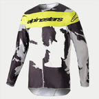 Alpinestars 2023 Racer Tactical Jersey, maglia da motocross, Cast Gray Camo e Giallo Fluo, caratterizzata da un motivo mimetico grigio e nero con un pannello giallo brillante sul petto e logo Alpinestars, abbigliamento tecnico a maniche lunghe resistente per corse off-road
