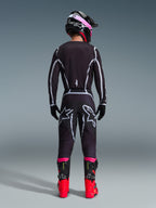 Pilota di motocross visto da dietro che indossa il completo Alpinestars 2026 Fluid Apex, maglia e pantaloni neri con linee geometriche grigie e loghi a stella, casco nero con dettagli rosa, stivali rosso acceso e neri, abbigliamento da gara motocross coordinato
