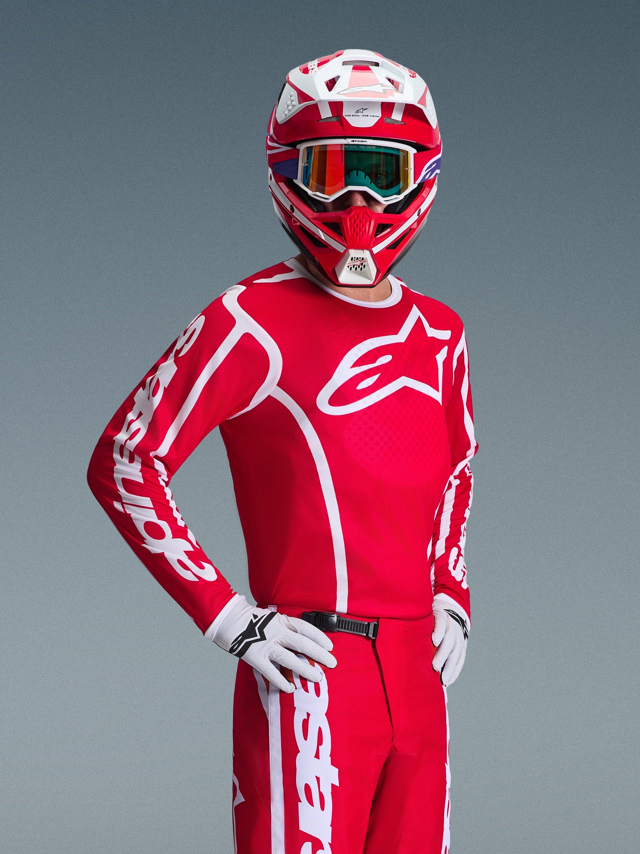 Pilota di motocross con maglia Alpinestars Fluid Apex 2026 in rosso e bianco, casco coordinato rosso e bianco con occhiali, guanti bianchi e pantaloni rossi, loghi bianchi audaci e vestibilità atletica, outfit coordinato per gare off-road