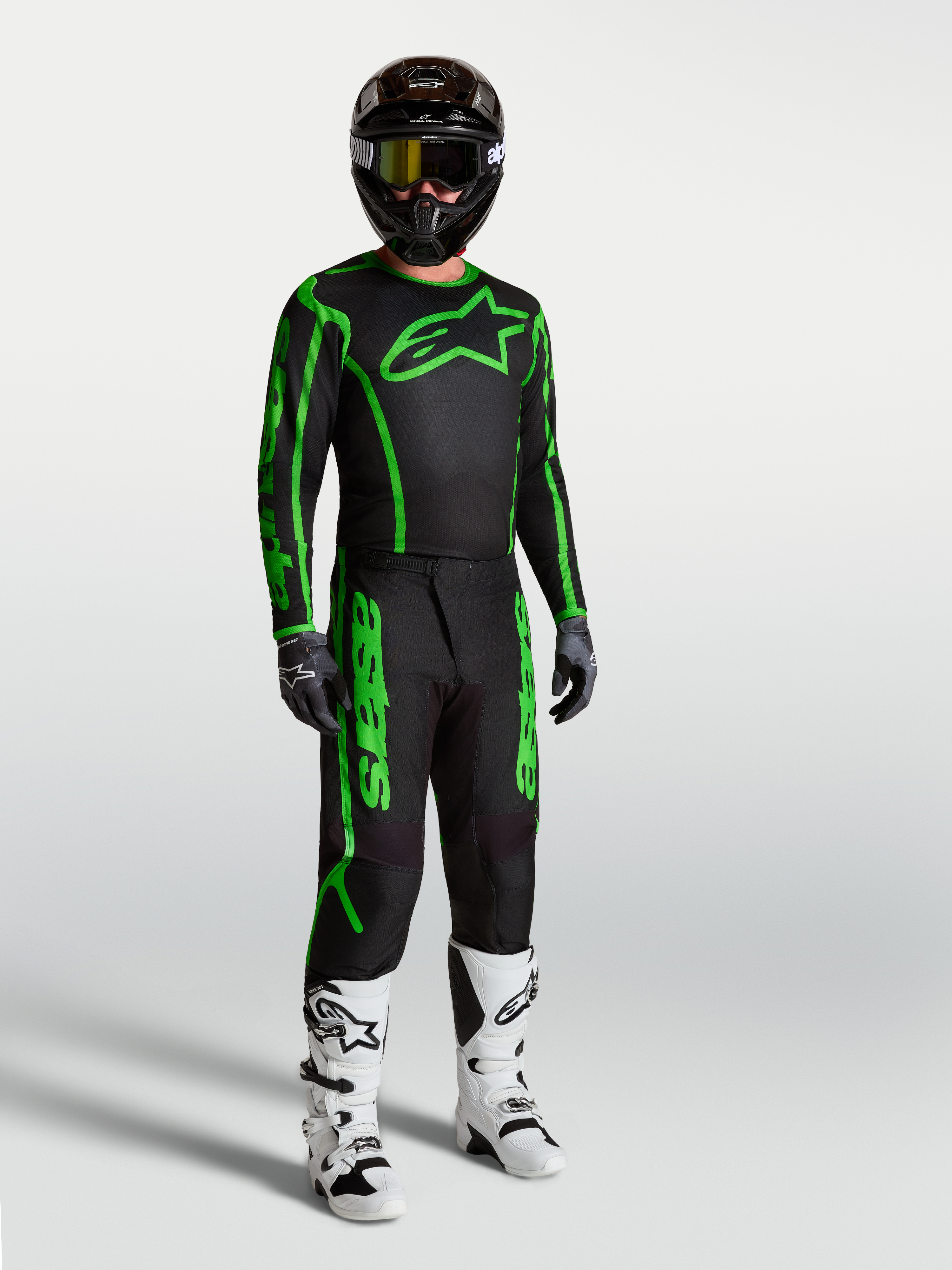 Alpinestars Maglia Fluid Apex V2, maglia motocross da uomo, nera e verde fluo, con pantaloni e stivali coordinati.