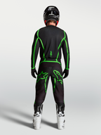 Alpinestars Pantaloni Fluid Apex V2, pantaloni da motocross da uomo, neri e verdi fluo, vista posteriore di un pilota con stivali bianchi.