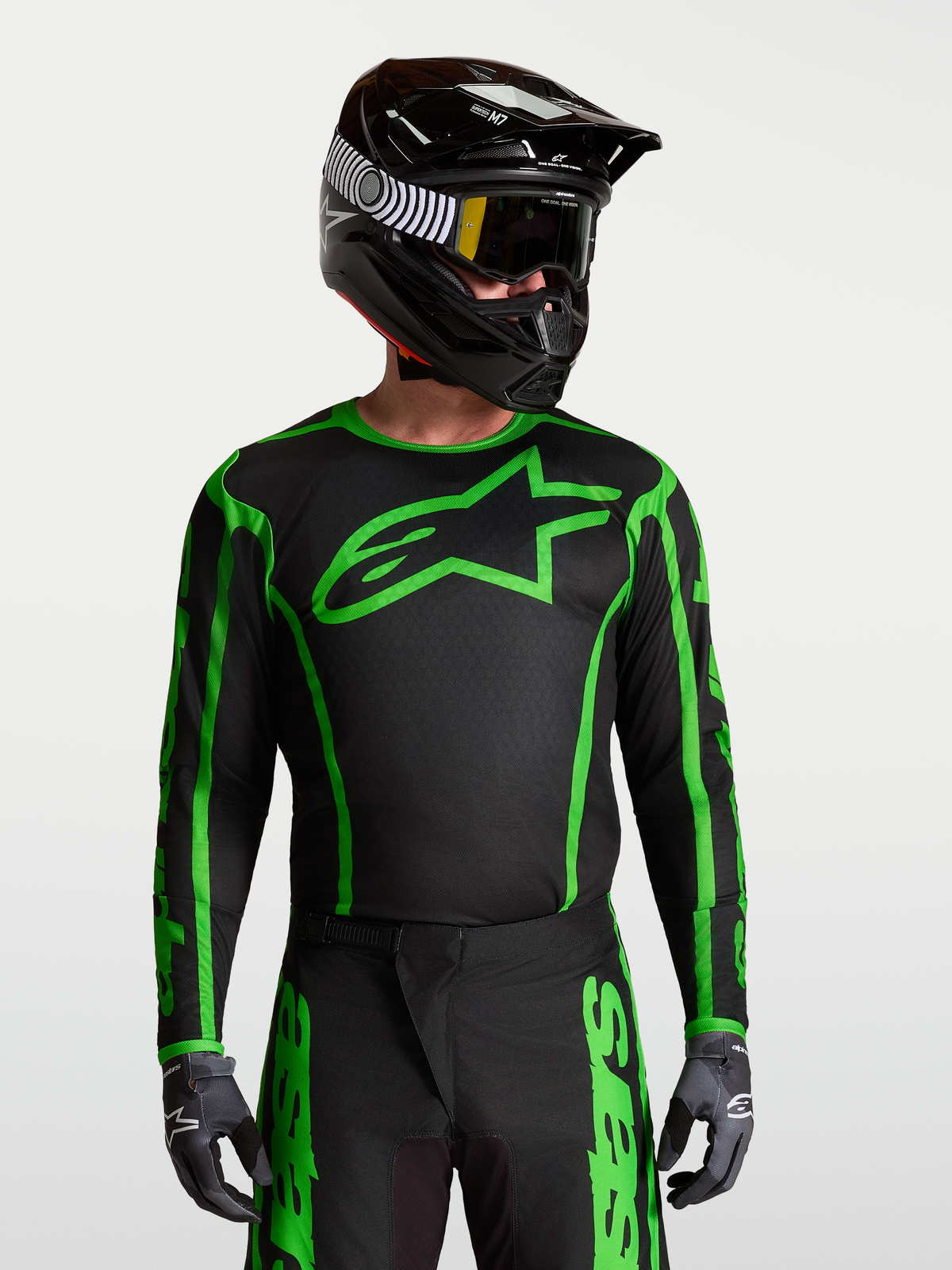 Alpinestars Maglia Fluid Apex V2, maglia da motocross uomo in poliestere nero e verde, traspirante e anti-umidità, indossata con casco.