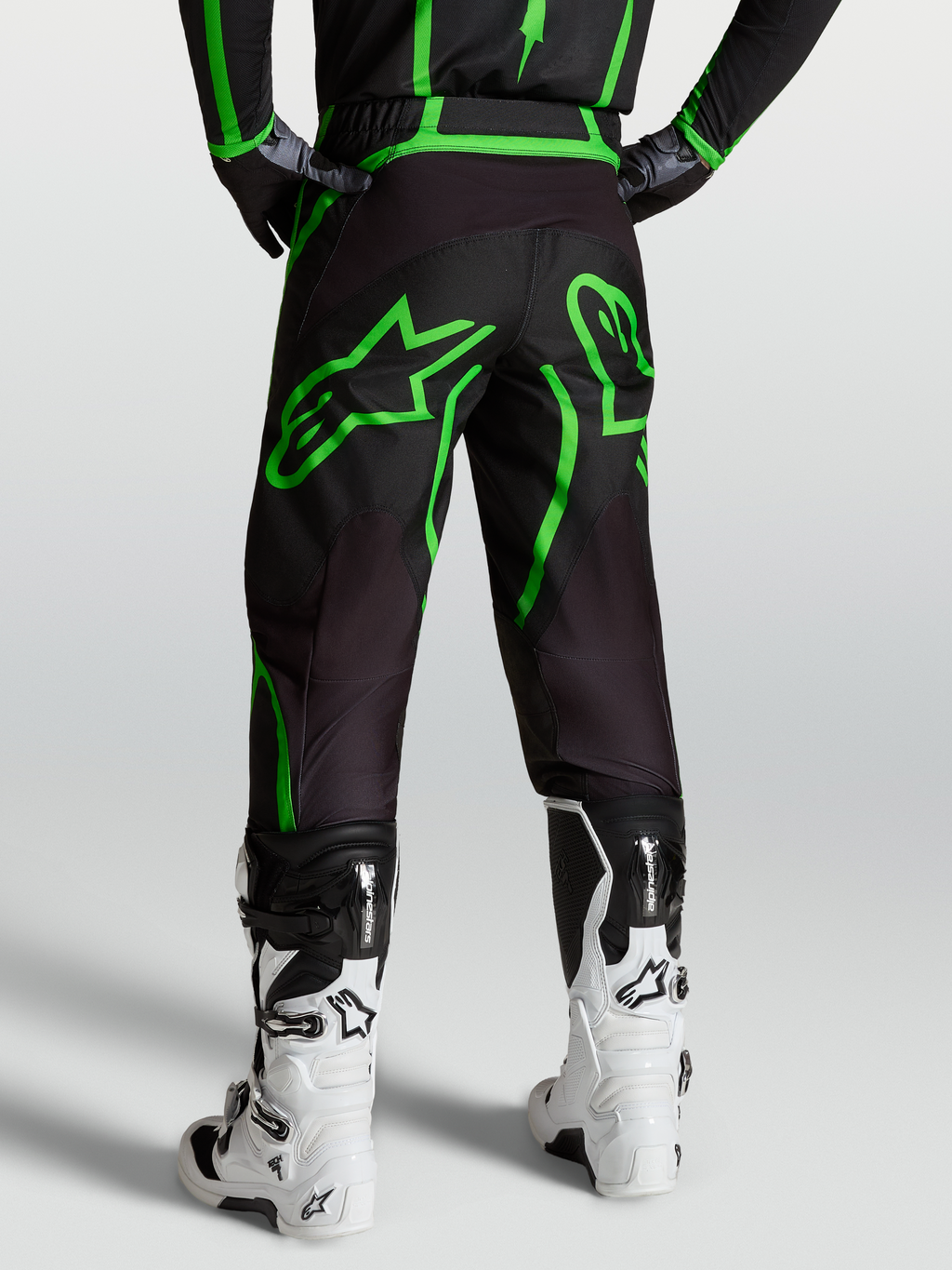 Alpinestars Pantaloni Fluid Apex V2, pantaloni motocross da uomo, nero e verde fluo, vista posteriore su modello con stivali bianchi.