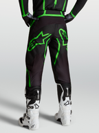 Alpinestars Pantaloni Fluid Apex V2, pantaloni motocross da uomo, nero e verde fluo, vista posteriore su modello con stivali bianchi.