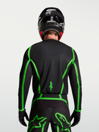 Alpinestars Maglia Fluid Apex V2, maglia da motocross per uomo, nera e verde fluorescente, vista posteriore su modello con retro allungato per maggiore copertura