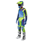 Alpinestars Racer Hoen Jersey 2024, maglia da motocross, giallo fluo e blu night navy, indossata da un pilota con pantaloni coordinati, casco e stivali bianchi, abbigliamento professionale da gara per guida fuoristrada