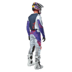 Pilota di motocross visto da dietro con la maglia Alpinestars 2024 Racer Hoen in Light Gray Hot Orange Black, pannello posteriore blu navy con logo a stella arancione, maniche viola, indossata con pantaloni da gara coordinati e stivali bianchi.