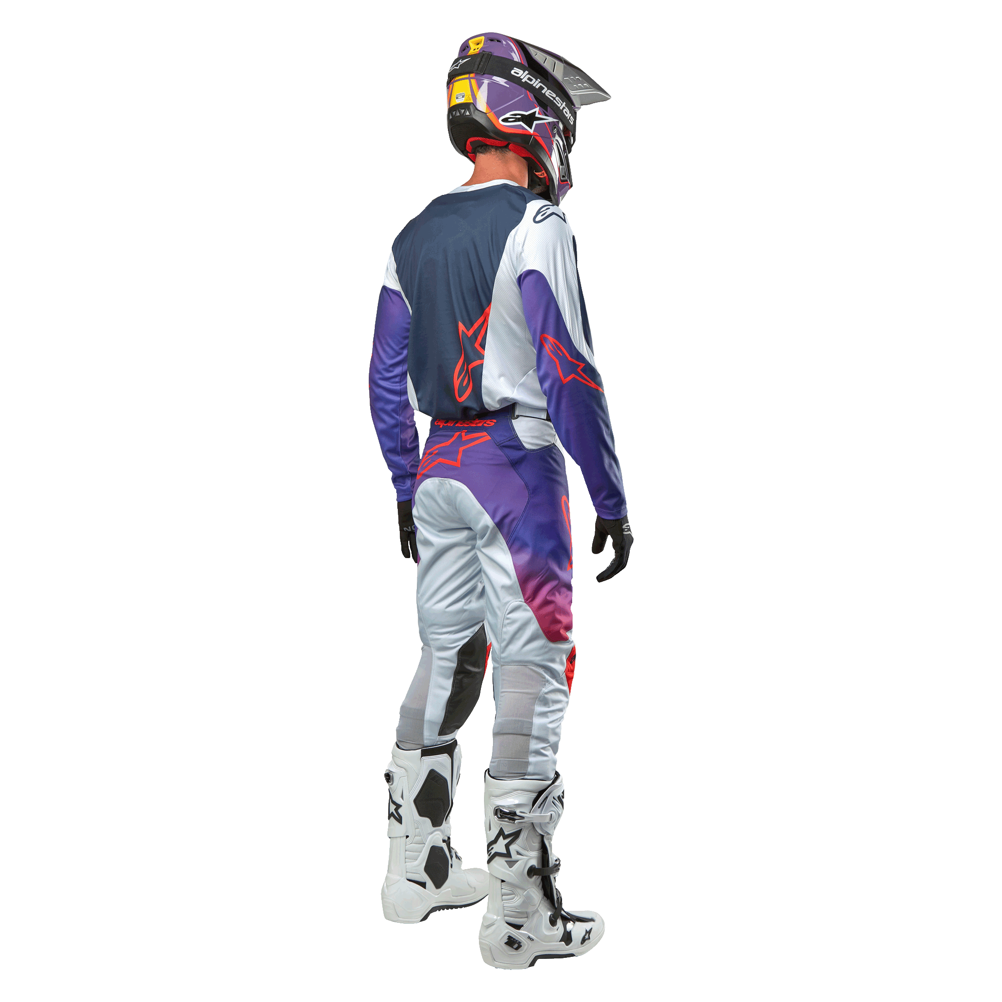 Pilota di motocross visto da dietro con la maglia Alpinestars 2024 Racer Hoen in Light Gray Hot Orange Black, pannello posteriore blu navy con logo a stella arancione, maniche viola, indossata con pantaloni da gara coordinati e stivali bianchi.