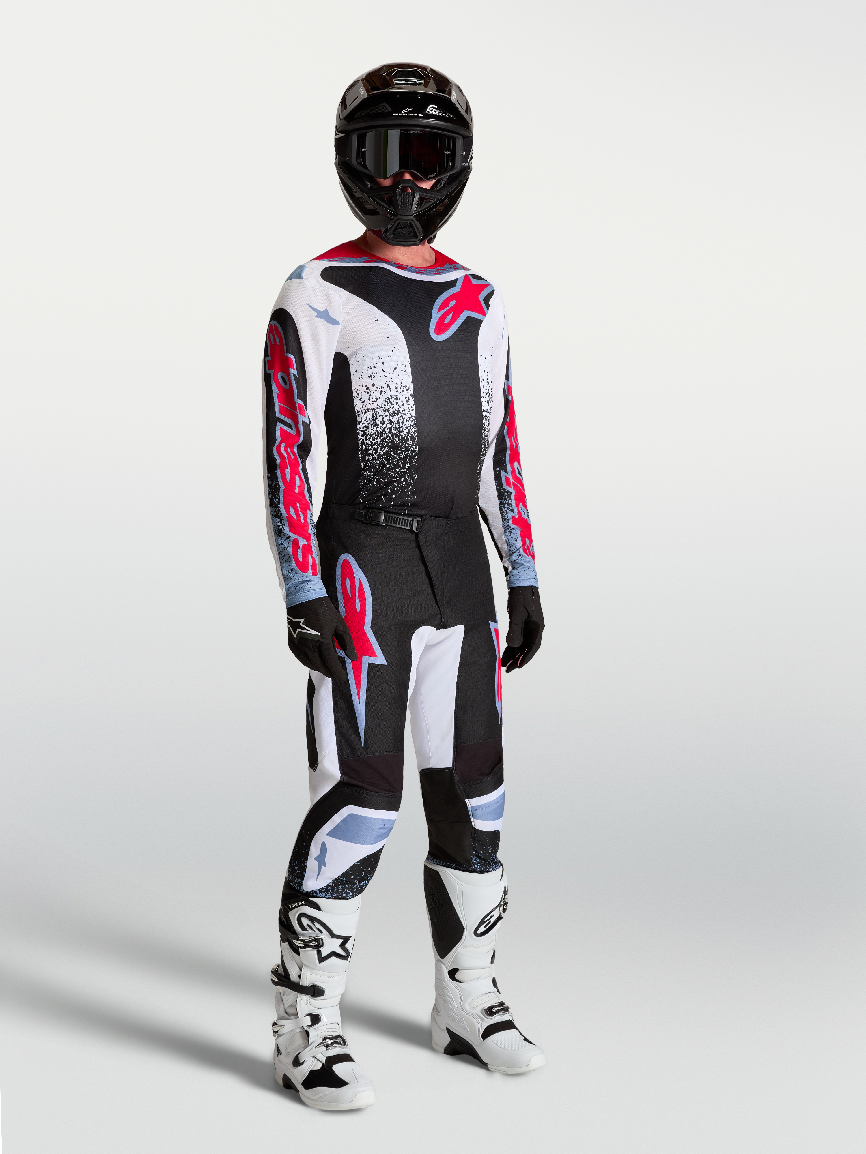 Alpinestars Maglia Fluid Drag, maglia da motocross da uomo, nero, bianco e rosso fluo, in tessuto tecnico traspirante, indossata da un modello con equipaggiamento completo da off-road