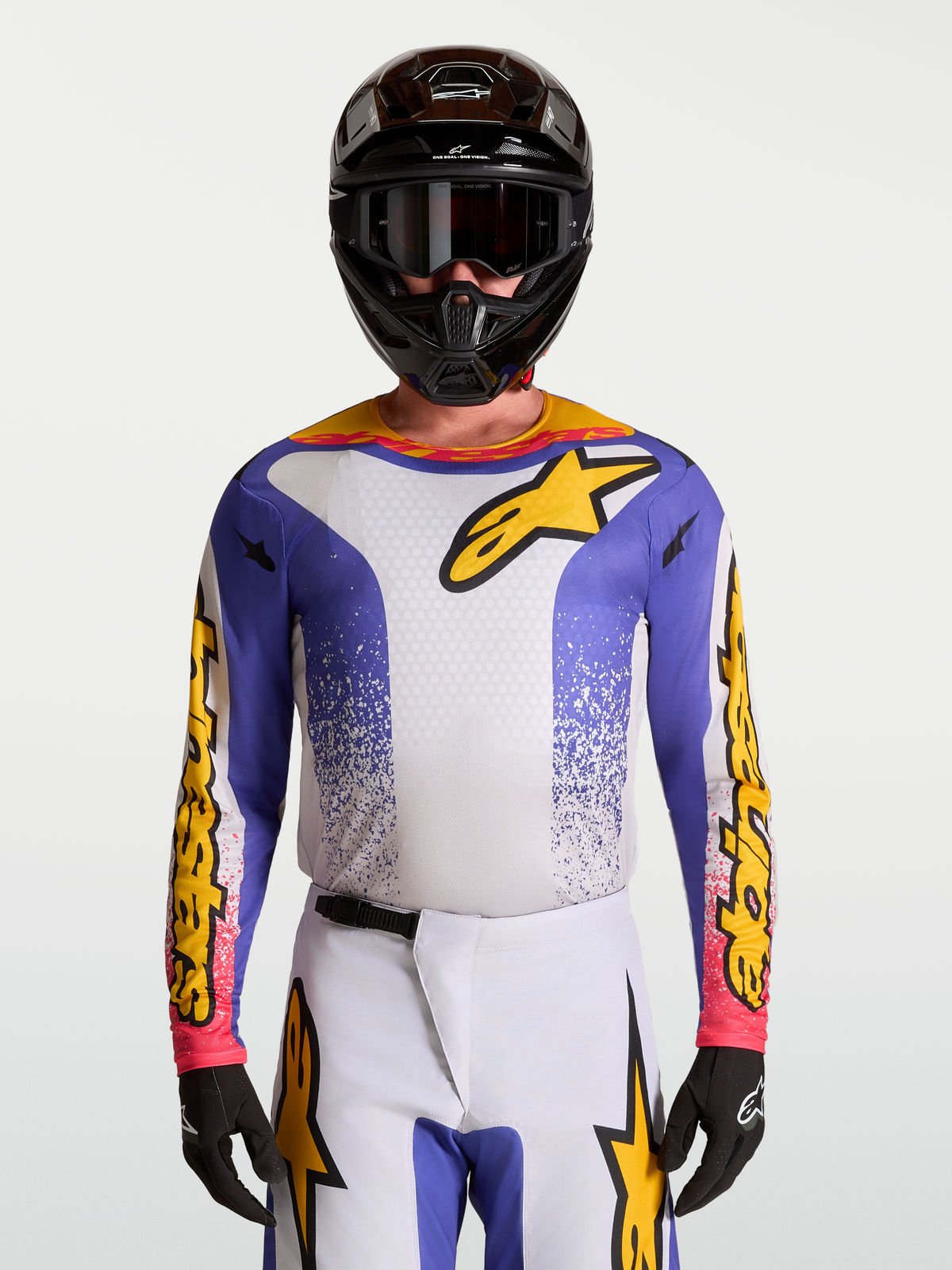 Alpinestars Maglia Fluid Drag, maglia da motocross da uomo, blu e oro, in tessuto leggero traspirante, indossata da un modello con casco e guanti, ideale per sessioni off-road