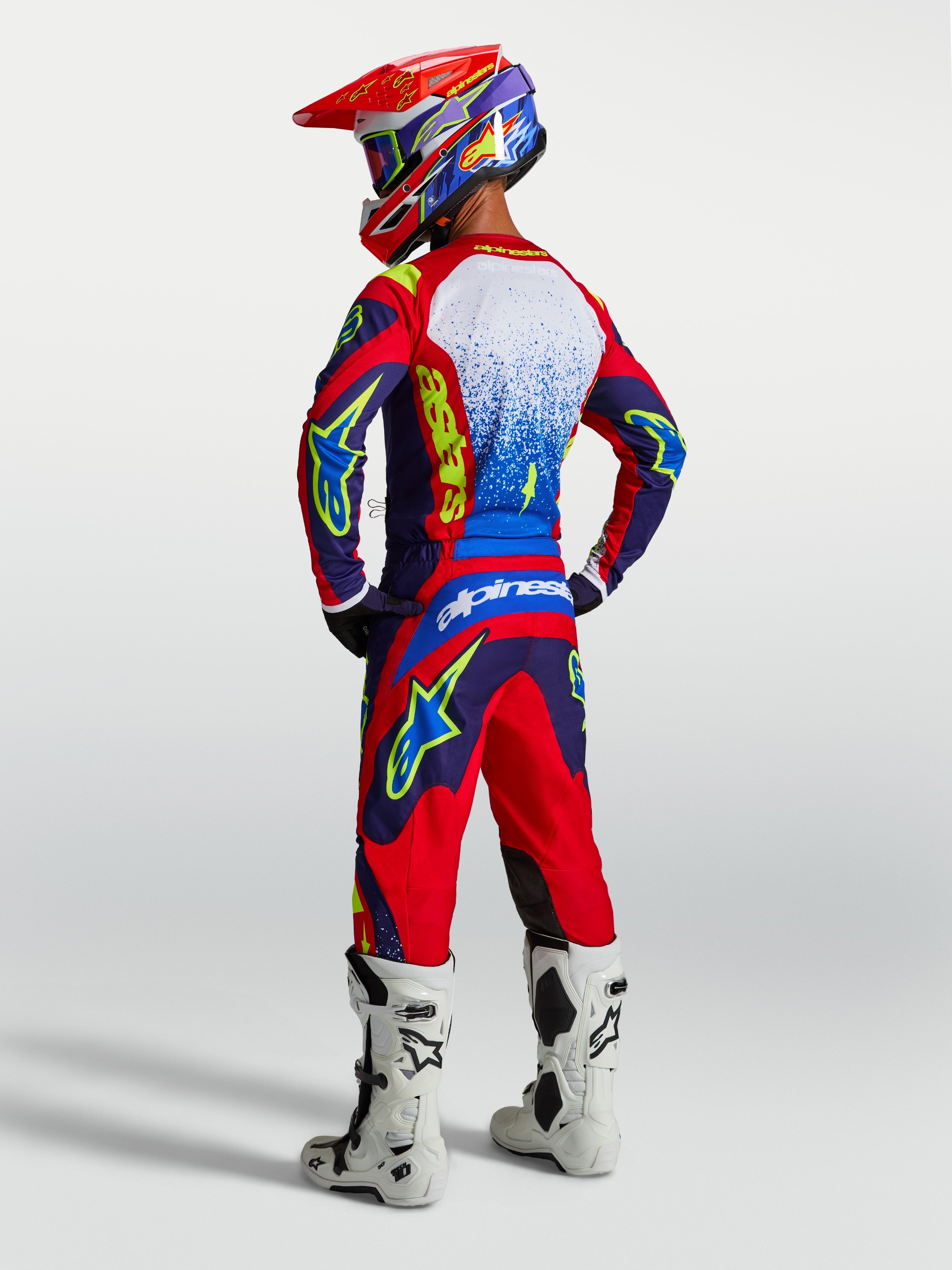 Alpinestars Maglia Fluid Drag, maglia da motocross da uomo, blu e rossa, vista posteriore su modello con stivali bianchi