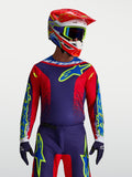 Alpinestars maglia Fluid Drag, maglia motocross da uomo, blu navy e rosso fuoco, in poliestere traspirante per prestazioni fuoristrada, indossata con casco coordinato.