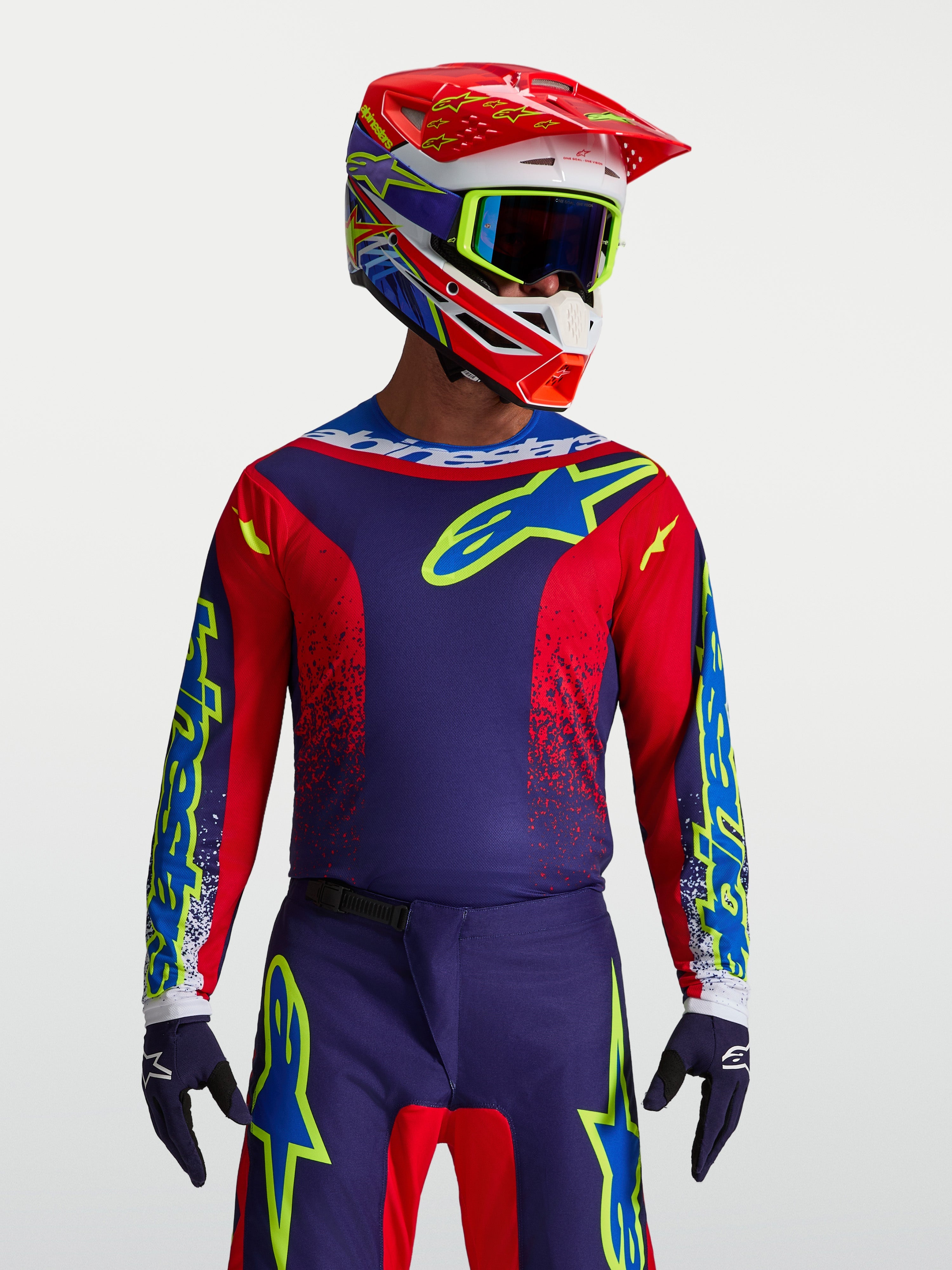 Alpinestars maglia Fluid Drag, maglia motocross da uomo, blu navy e rosso fuoco, in poliestere traspirante per prestazioni fuoristrada, indossata con casco coordinato.
