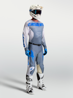 Alpinestars Maglia Racer Amber, maglia da motocross grigia e blu per uomo, indossata da un modello con casco e stivali bianchi.