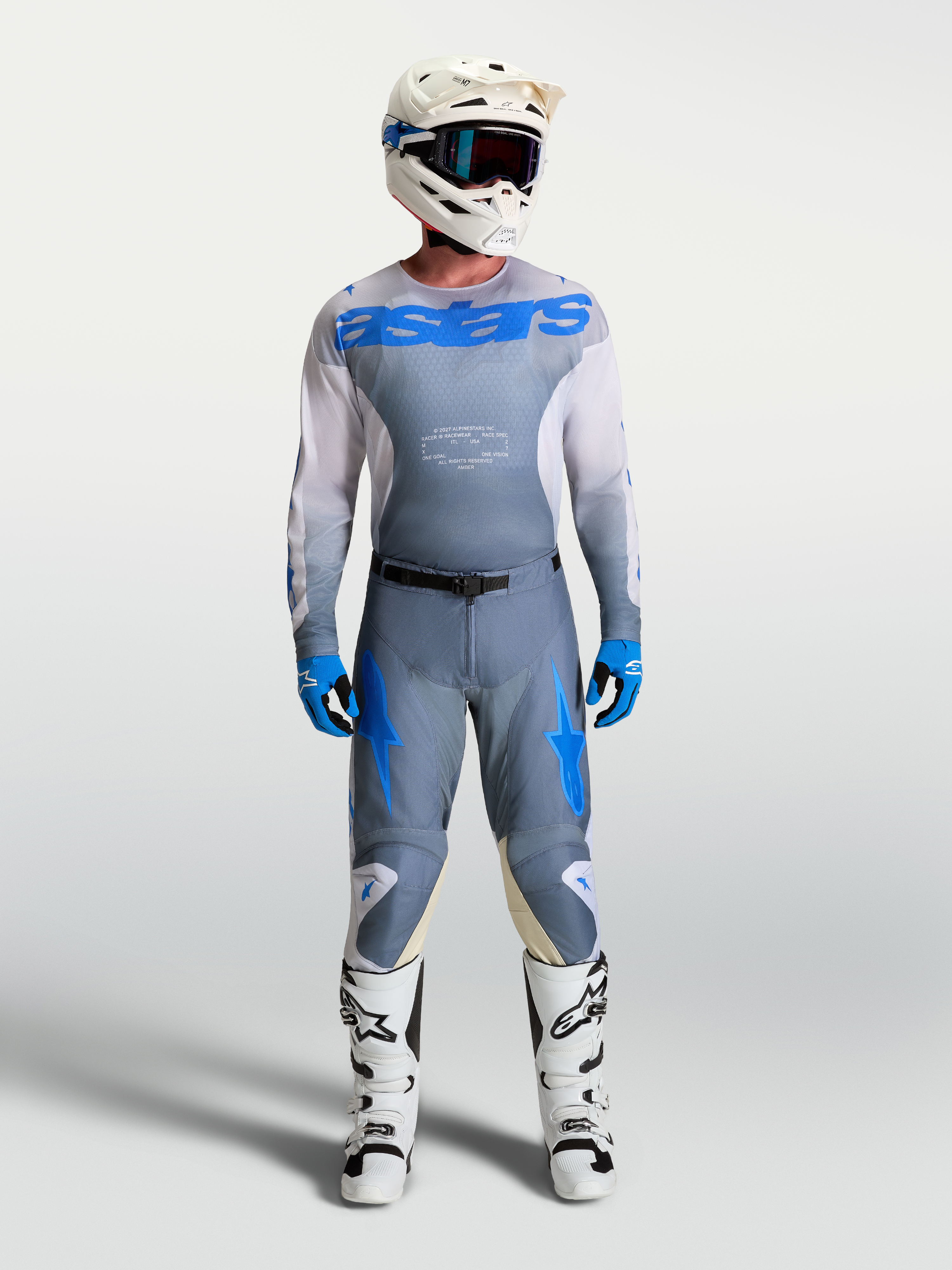 Alpinestars Pantaloni e Maglia Racer Amber, completo motocross da uomo, grigio e blu, indossato con stivali e casco bianchi, ideale per guida fuoristrada e motocross, materiali tecnici traspiranti.