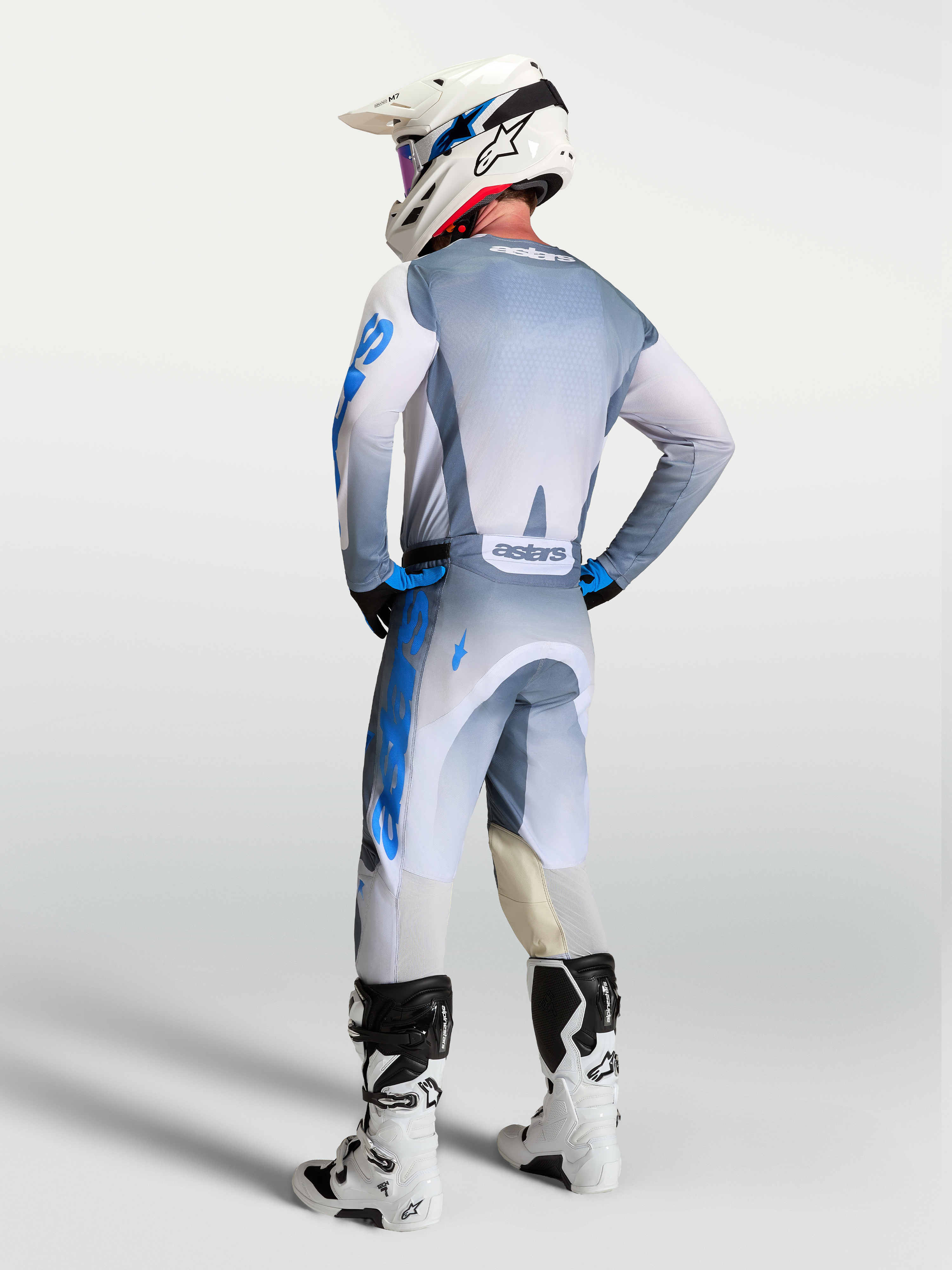 Alpinestars Pantaloni Racer Amber e Gear Set 2027, abbigliamento da motocross uomo, grigio e blu, vista posteriore su pilota.