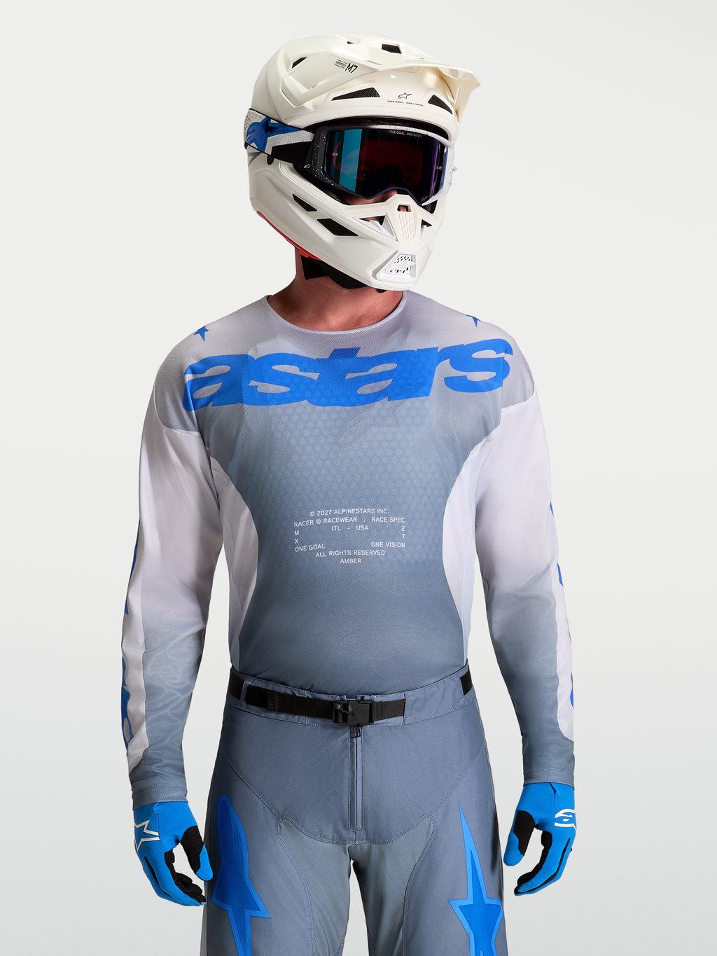 Alpinestars Maglia Racer Amber, maglia motocross da uomo, grigio fumo e blu UCLA, con casco e maschere bianche.