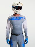 Alpinestars Maglia Racer Amber, maglia motocross da uomo, grigio fumo e blu UCLA, con casco e maschere bianche.