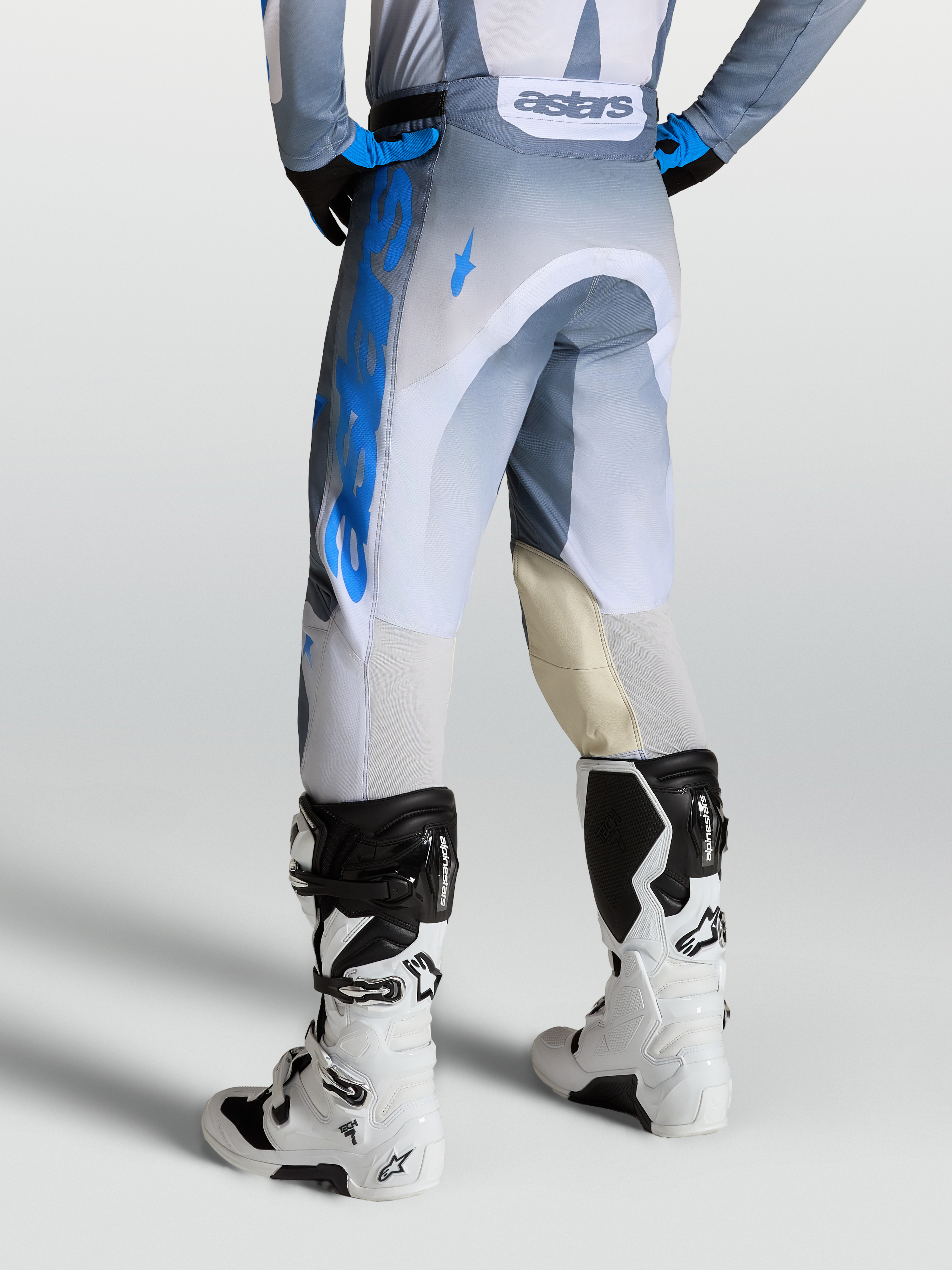 Alpinestars Pantaloni Racer Amber, pantaloni motocross da uomo, grigio e blu, con pannelli interni al ginocchio in pelle e ventilazione posteriore, indossati con stivali Tech 7