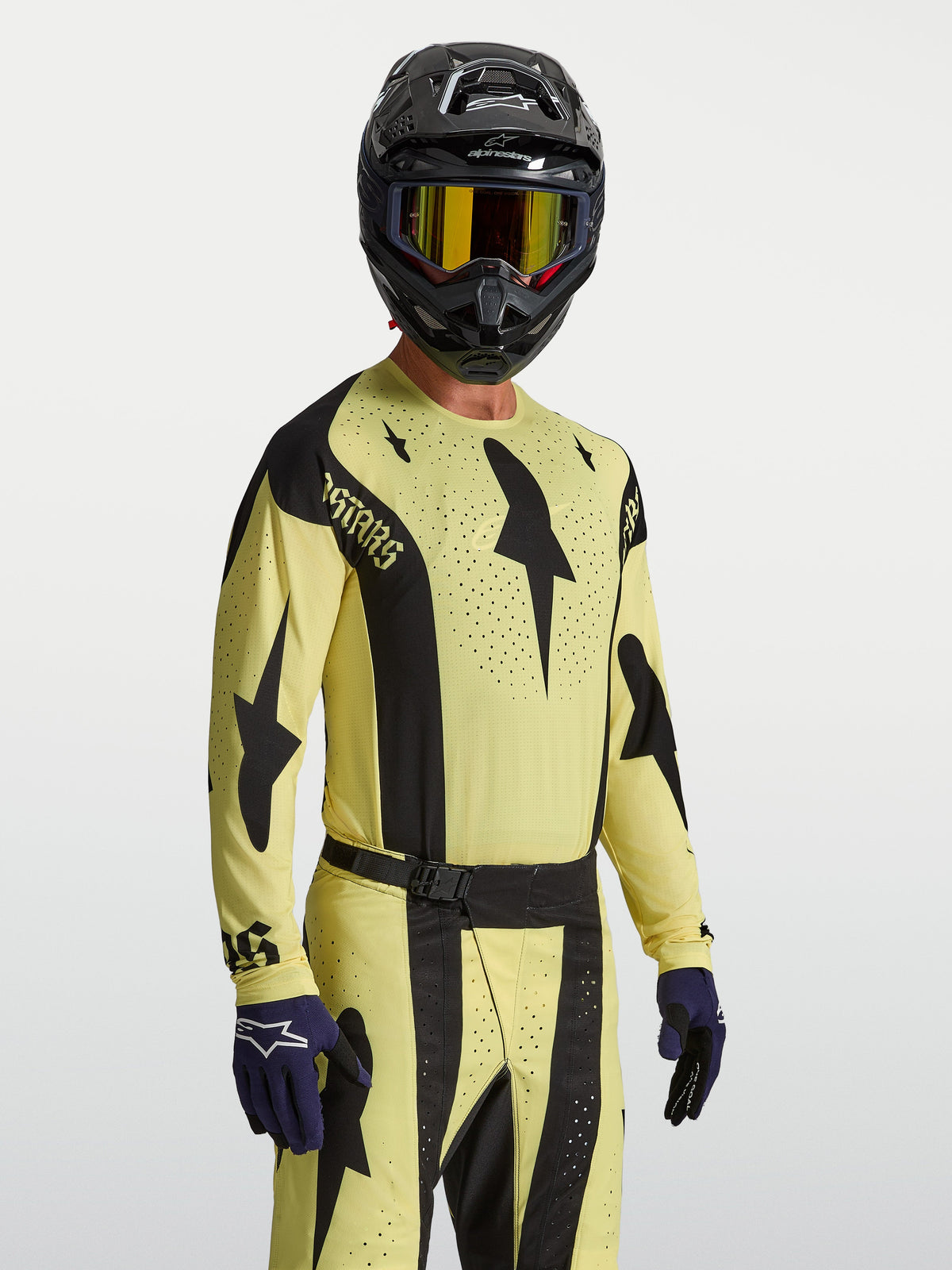 Alpinestars maglia Techstar Atrox, maglia da motocross da uomo gialla e nera, fori tagliati al laser per ventilazione e vestibilità atletica da gara, indossata con casco e guanti.