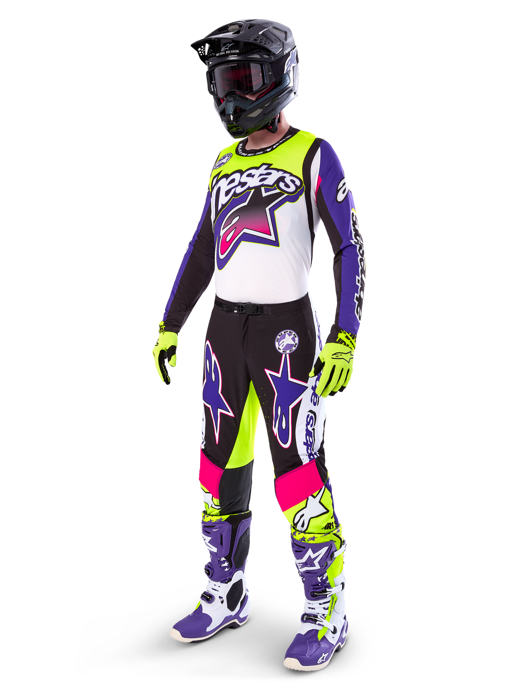 Pilota di motocross che indossa l'abbigliamento Alpinestars Limited Edition Supertech Dirt Studios®, schema colori bianco, viola e giallo fluo, pantaloni neri con grandi loghi a stella viola e rosa, guanti giallo neon, stivali da gara viola e bianchi, casco nero, kit professionale completo per prestazioni off-road