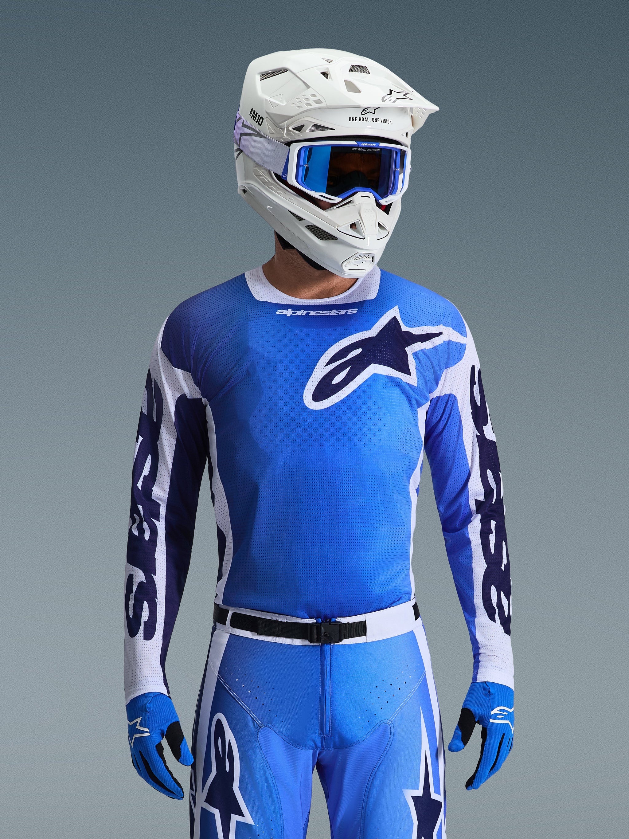 Alpinestars 2026 Racer Air Portl Jersey in blu Ucla e bianco, maglia da motocross con struttura in mesh traspirante e grande logo a stella, indossata da un pilota con pantaloni coordinati, casco bianco e occhiali blu per un set da gara off-road coordinato.