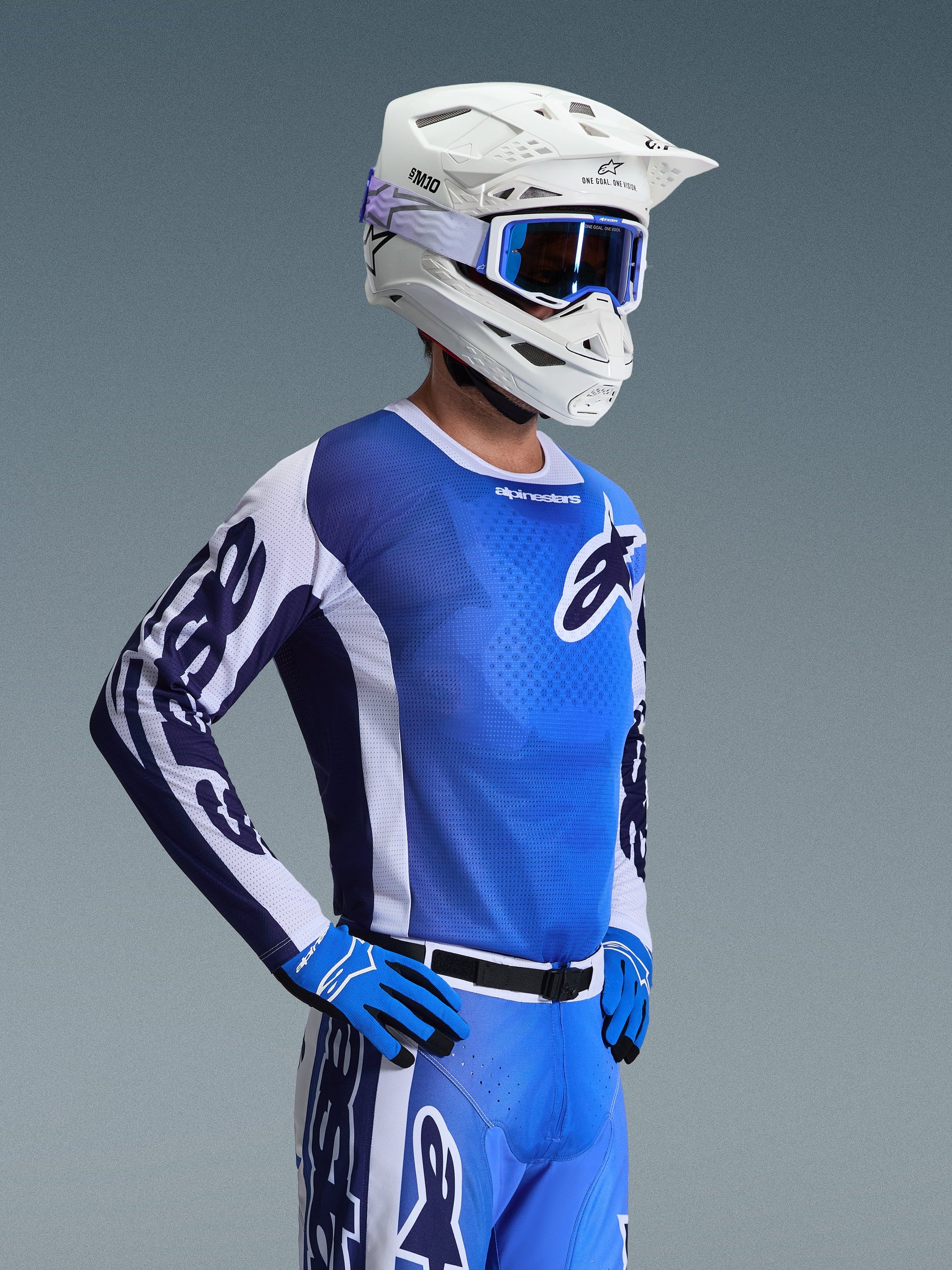 Maglia Alpinestars 2026 Racer Air Portl, maglia da motocross, blu UCLA e bianco, indossata con casco bianco, maschera blu e guanti coordinati, caratterizzata da un design in mesh traspirante per gare off-road ad alte temperature.