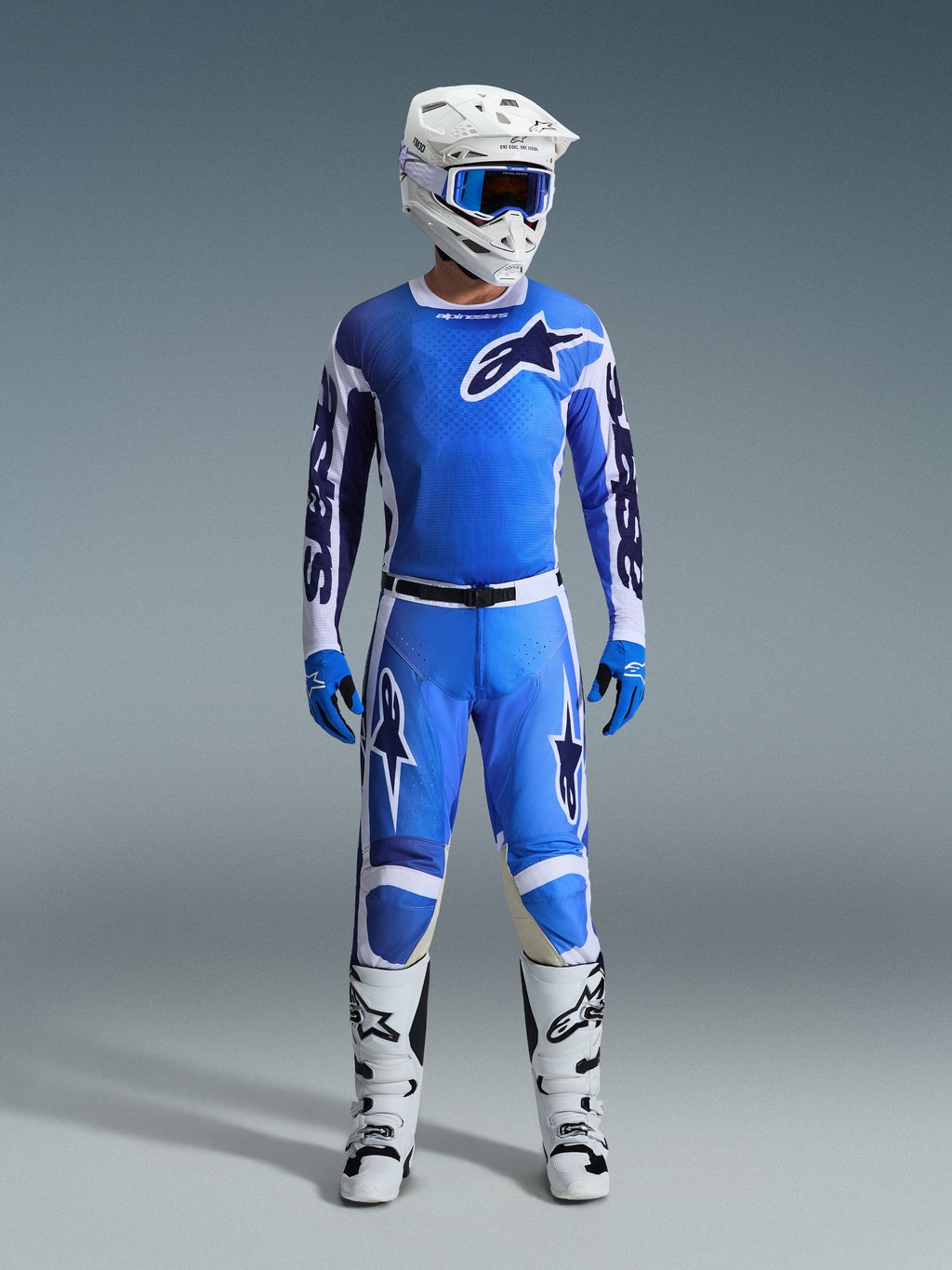 Pilota di motocross con maglia Alpinestars Racer Air Portl 2026 in Ucla Blue White, pantaloni da motocross blu coordinati, casco bianco con occhiali blu, guanti blu e stivali bianchi, set completo di abbigliamento professionale per corse off-road