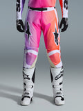 Alpinestars 2026 Racer Air Portl Pants, pantaloni da motocross, vivace sfumatura viola, rosa e arancione, con vistosi loghi a stella sulle cosce, indossati con stivali da corsa bianchi e guanti neri, progettati per la guida off-road ad alte prestazioni.